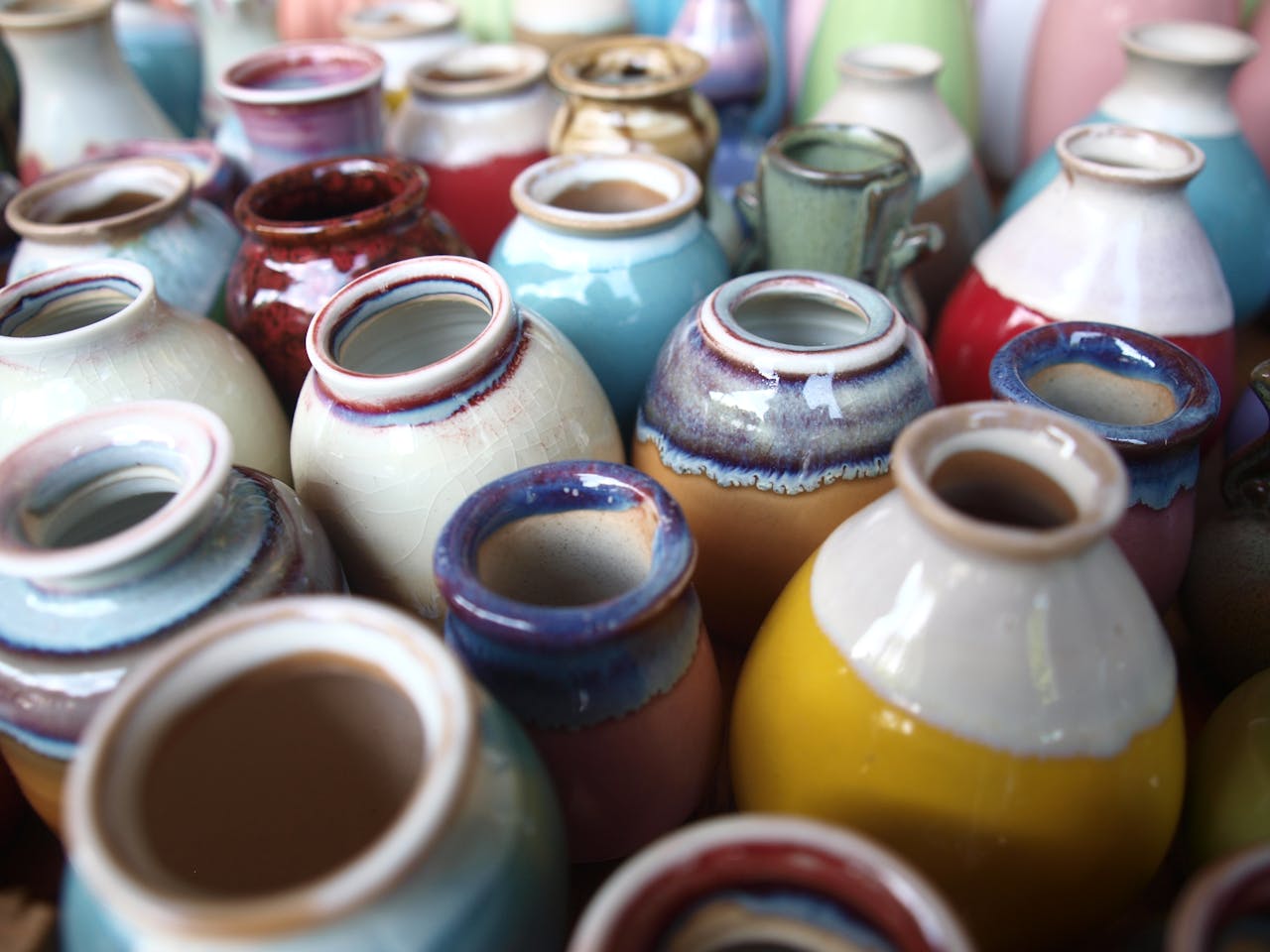 hero-img Intricate handmade ceramic jugs in a vibrant mix of colors and glazes, showcasing traditional pottery art.
